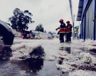 Imagen de integrantes del Cuerpo de Bomberos del Distrito Metropolitano de Quito despejando granizo de la calle.