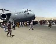 Cientos de personas corren al lado de un avión de carga C-17 de la Fuerzas Aérea de Estados Unidos que trata de despegar en la pista del aeropuerto internacional de Kabul.