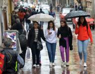 Ciudadanos se protegen de la lluvia en la ciudad de Cuenca