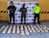 Fotografía cedida por la Policía de Colombia que muestra a uniformados mientras custodian 53,5 kilos de heroína incautada en Buesaco, Nariño.