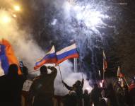 Personas celebran el reconocimiento de independencia ondeando banderas de Rusia en el centro de Donetsk.
