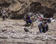 Personas intentan recuperar sus pertenencias en una zona afectada por la crecida del río Irpavi este jueves, en La Paz (Bolivia).
