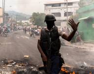 Un policía da indicaciones junto a una barricada en llamas durante una jornada de protesta en Haití.