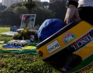 Un seguidor del automovilista brasileño Ayrton Senna sostiene un casco frente a la tumba del piloto en Sao Paulo, este miércoles, cuando se conmemoran tres décadas de su fallecimiento.