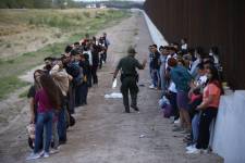 Un grupo de migrantes permanecen junto al muro de la frontera con México en una foto de Archivo.