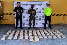 Fotografía cedida por la Policía de Colombia que muestra a uniformados mientras custodian 53,5 kilos de heroína incautada en Buesaco, Nariño.