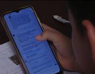 Imagen de una madre de familia revisan su celular por el cual se envían deberes.