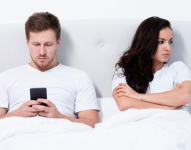 Imagen referencial. Hombre viendo su celular mientras su pareja está enojada.
