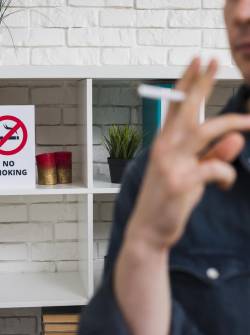 Hombre fumando en un lugar que no es permitido consumir tabaco.