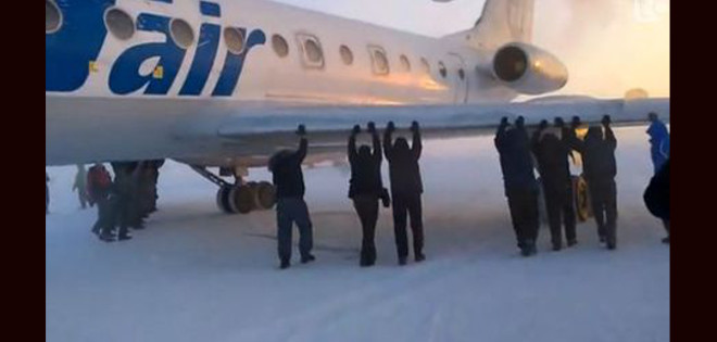 Pasajeros empujan su avión en un aeropuerto siberiano para poder despegar