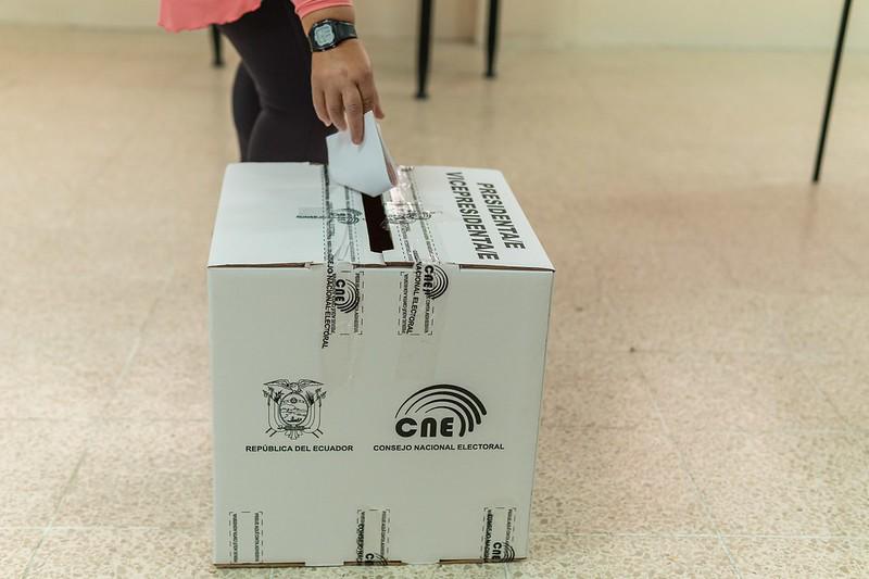 Imagen de una persona colocando su papeleta marcado dentro de una urna de votos.