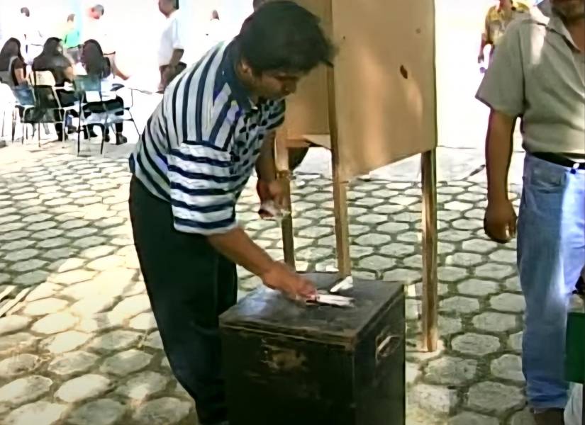 Persona insertando su voto en una urna de acero
