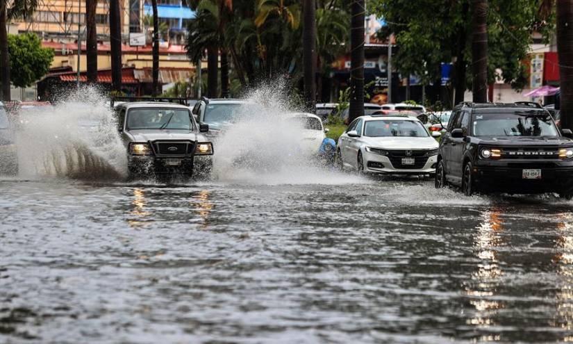 Vehículos transitan por una calle inundada debido a las fuertes lluvias hoy, en el balneario de Acapulco, estado de Guerrero, México.