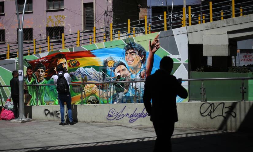 Personas observan un mural, frente al estadio Hernando Siles, en honor a jugadores históricos de las selecciones de Bolivia y Argentina, en La Paz.