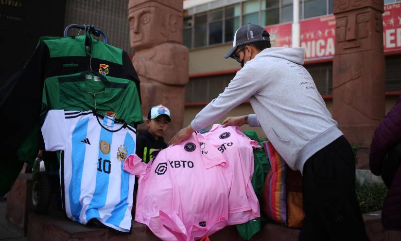 Un hombre vende hoy camisetas de los seleccionados de Bolivia y Argentina, así como del Inter de Miami, club de Leo Messi, en una calle de La Paz.