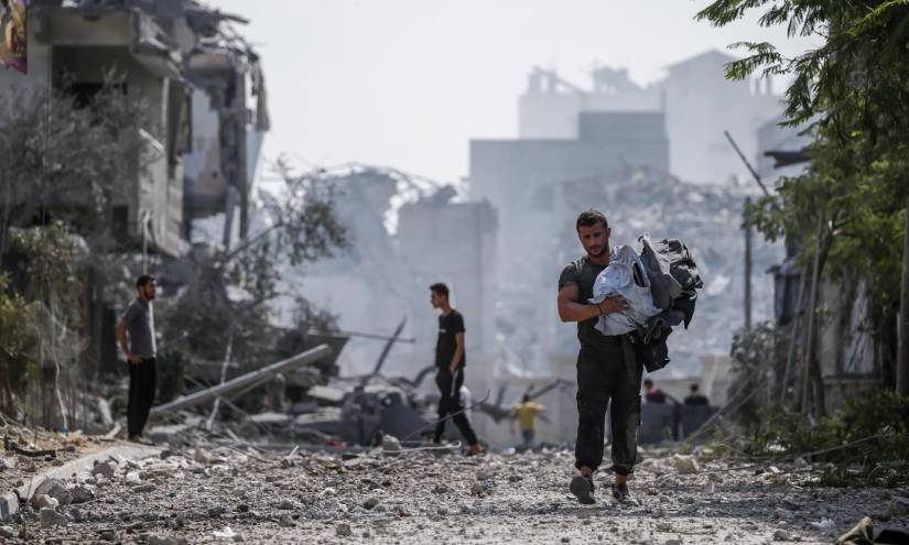 Palestinos caminan entre ruinas en el barrio de Al Ramal de Gaza tras un bombardeo israelí.