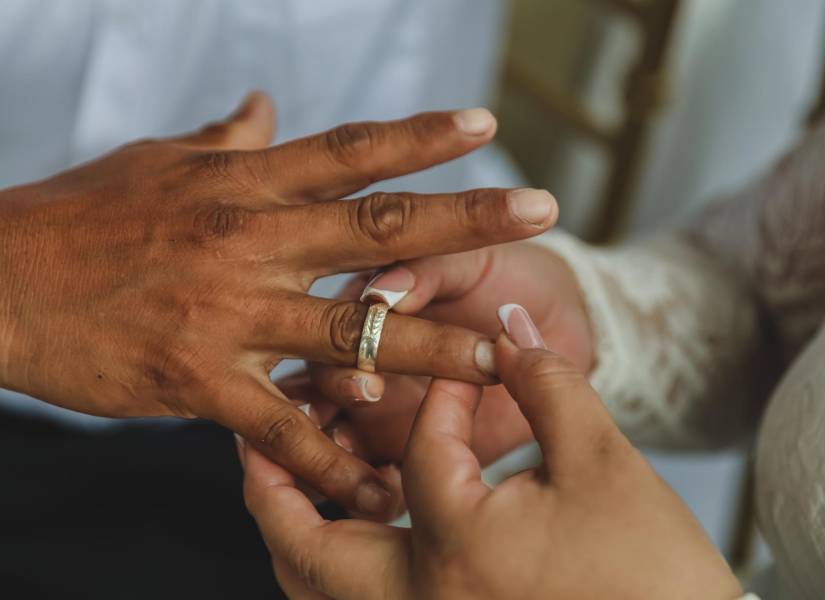 Imagen de una pareja poniéndose sus anillos de casados, en la Concha Acústica de Samanes.