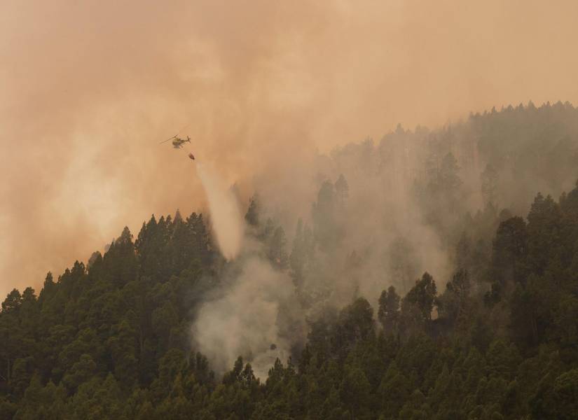 Un helicóptero del dispositivo de extinción del incendio forestal de Tenerife lanza agua sobre uno de los focos de este fuego