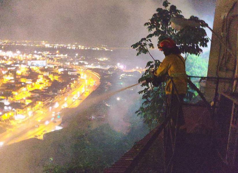 Imagen de un bombero direccionando agua hacia el incendio en el Cerro del Carmen en Guayaquil.