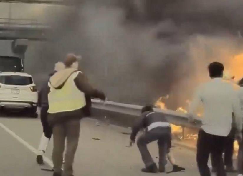 Personas tratando de sacar al hombre del vehículo incendiado.