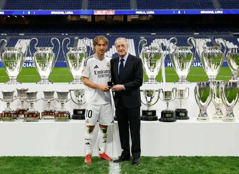 Luka Modric posando junto a Florentino Pérez con los trofeos conseguidos por el croata.
