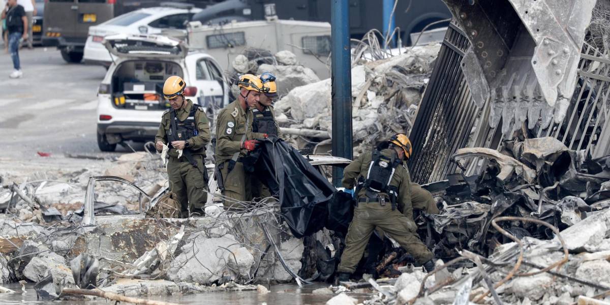Fuerzas de seguridad israelíes retiran un cuerpo frente a la destruida comisaría de policía de Sderot, cerca de la frontera con Gaza. EFE/EPA/ATEF SAFADI
