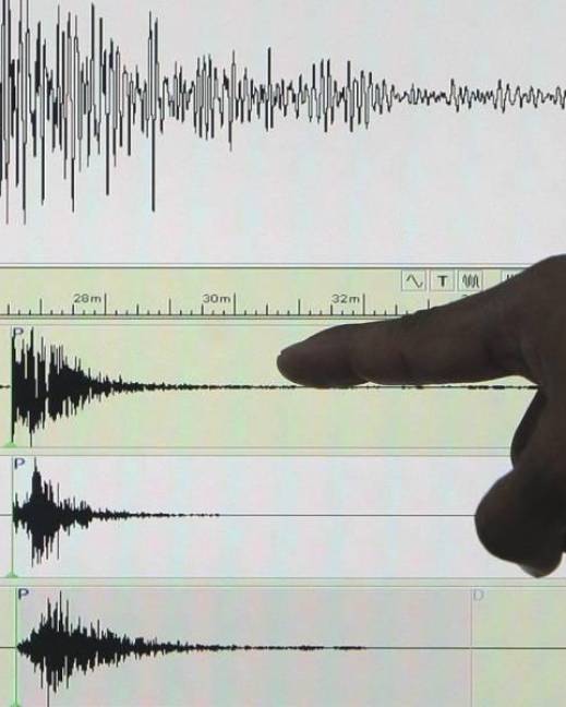 Vista de una persona que señala un sismógrafo, en una fotografía de archivo