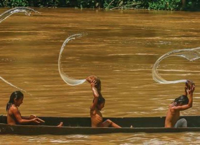 Un grupo de niños juega en una canoa sobre el río Cononaco al pie de la comunidad de Bameno.