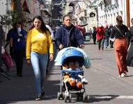 Una madre de familia pasea a su hijo en un coche por las calles del Centro Histórico de Quito.