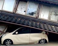Un auto atrapado de bajo de una casa, tras el sismo en Japón.