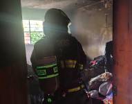 Un efectivo del CBQ interviene en la vivienda donde ocurrió el incendio, en Puembo.