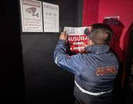 Uno de los técnicos de la AMC coloca los sellos de clausura en uno de los locales.