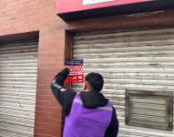 Un funcionario de Arcsa coloca el sello en la puerta del local clausurado.