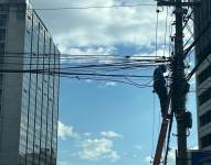 Un obrero repara los cables en el norte de Quito.