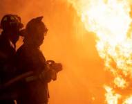 Imagen de referencia de dos bomberos luchando contra las las llamas.