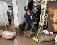 Consuelo Arias saca el lodo de su zapatería en la avenida La Gasca, noroccidente de Quito.