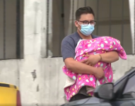 Imagen de un hombre sosteniendo un bebé en los exteriores de una casa de salud.