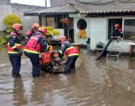 Los bomberos realizan labores para evacuar el agua acumulada en una vivienda de Conocoto.