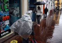 Una ciudadana se protege de la lluvia con un plástico en la ciudad de Cuenca, la tarde del 28 de octubre de 2024.