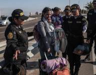 Policías hablan con migrantes en el paso fronterizo de control
