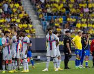Jugadores de ambos clubes esperando en el campo a que se atienda a la fanática.