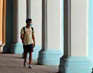 Un joven camina con mascarilla por unos portales en La Habana Vieja (Cuba). EFE/ Ernesto Mastrascusa/Archivo