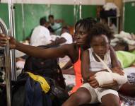 Daline Noel carga a su hija Bernard Lenise, quien permanece internada en el hospital Immaculée Conception.