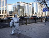 Una mujer que lleva equipo de protección personal (EPP) durante la pandemia de Covid-19 camina por una calle en Beijing el 26 de diciembre de 2022.