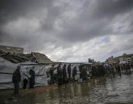 CIUDAD DE GAZA, 26 de noviembre, palestinos caminan a través de un charco cerca de tiendas de campaña improvisadas durante un día lluvioso en la Ciudad de Gaza.