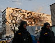 Trabajadores de emergencia ucranianos caminan frente a un edificio residencial dañado tras un ataque aéreo en Kiev el 14 de noviembre de 2025, en el contexto de la invasión rusa de Ucrania.