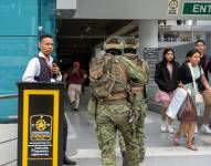 Soldados ecuatorianos persiguen hoy a un presunto delincuente mientras ciudadanos evacúan a pocas cuadras de la sede del canal de televisión TC.