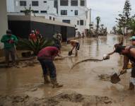 Fotografía de archivo, tomada el 15 de marzo, en la que se registró a un grupo de personas al ayudar al remover el lodo de una calle anegada por las fuertes lluvias, en el balneario de Punta Hermosa, al sur de Lima (Perú). EFE/Paolo Aguilar