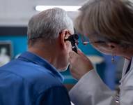 Una doctora utiliza un otoscopio para realizar una consulta de oído a un anciano durante su cita médica.