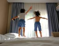 Imagen referencial de niños saltando en la cama de un hotel.
